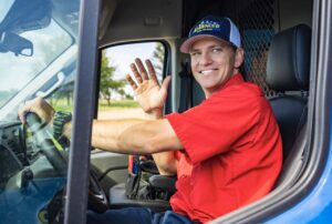 Advanced Home Services technician arriving to appointment, smiling and waving from driver's seat of service van.