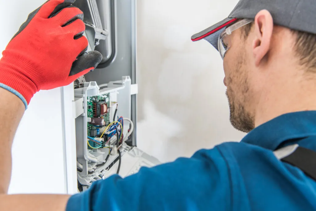 Technician servicing gas furnace system in a home.