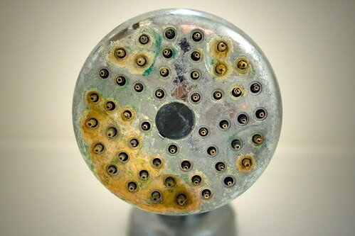 Hard water deposits and rust on a shower head, a common issue addressed with proper water heater maintenance for either a tanked or tankless water heater.